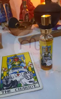Frasco de perfume ritualístico ao lado da carta O Carro